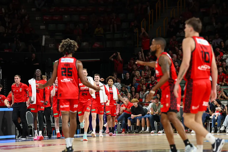 Perth Wildcats players and coaches celebrating courtside during an NBL game